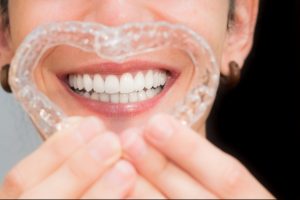 smiling woman making a heart with her invisible aligners for dental correction. mobile orthodontic