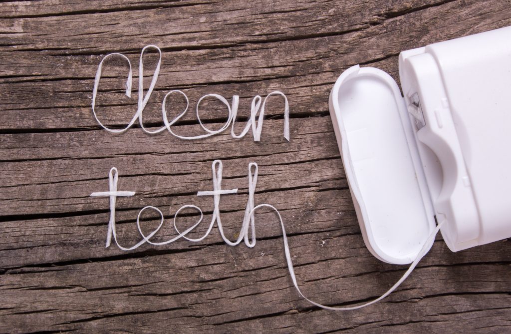 Words clean teeth of dental floss on an old wooden table