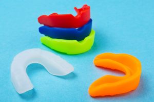 many colored boxing mouth guards lie on a blue background, sports concept