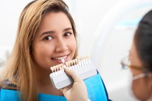 Pretty smiling young Asian woman having teeth whitening procedure