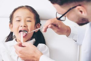 Friendly young dentist examining happy child teeth in dental clinic. Dentistry concept.