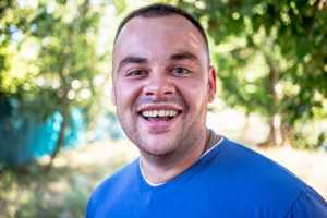 Young man in a blue T-shirt with a chipped tooth