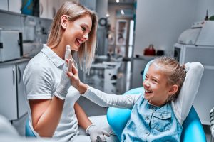 Baby cute girl gives five dentist. Little girl in the dentist's chair