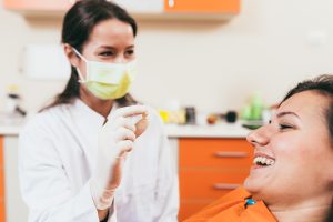 Happy dentist holding a tooth and satisfied patient after tooth extraction