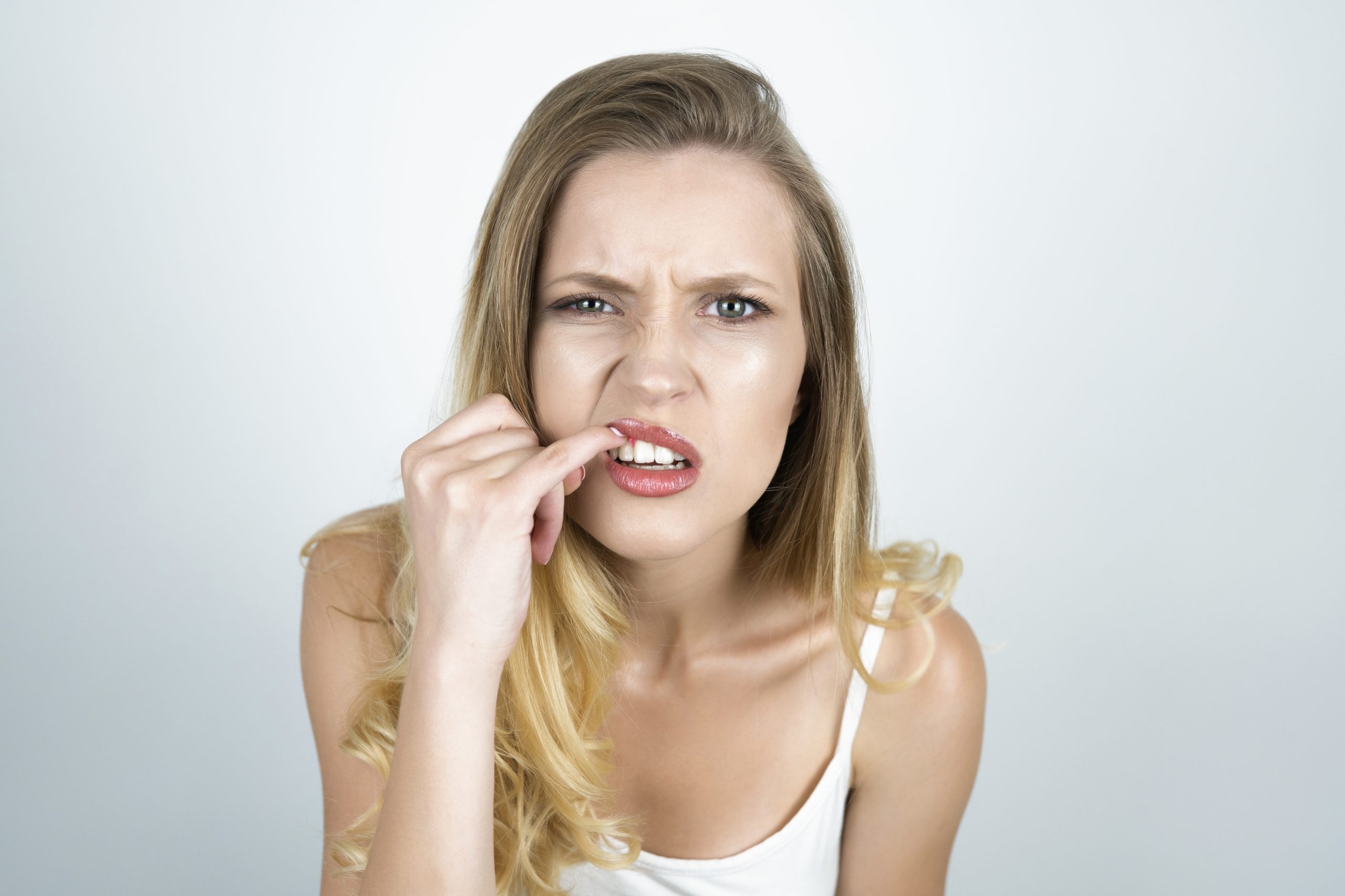 blond young woman showing her teeth with finger close up isolated white background.