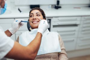 Woman getting a dental treatment at dentistry. Dentist examining the teeth of female patient with tools in clinic.