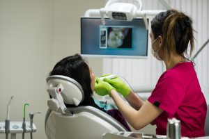 Dentist at work examining woman's teeth in dental clinic with remote camera. Picture of teeth is on the screen. dental technologies.