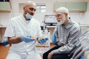 Handsome old man talking to the dendist. Two men in the dentist's office