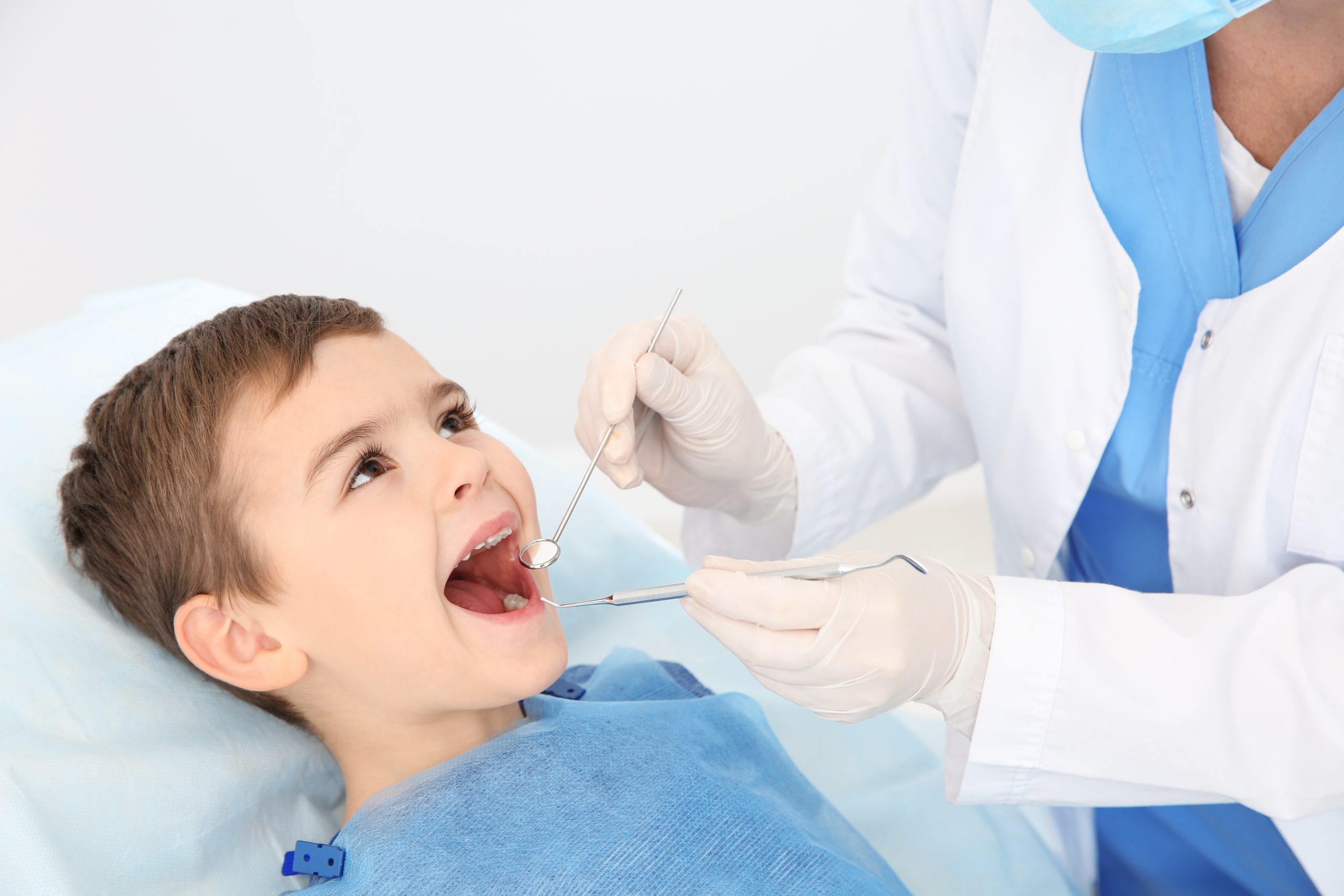 Dentist examining cute boy's teeth in modern clinic