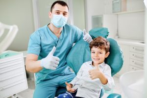 Happy dentist and child raised their thumb up at the dental clinic.