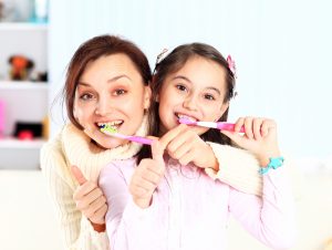 Mother and daughter brush their teeth.