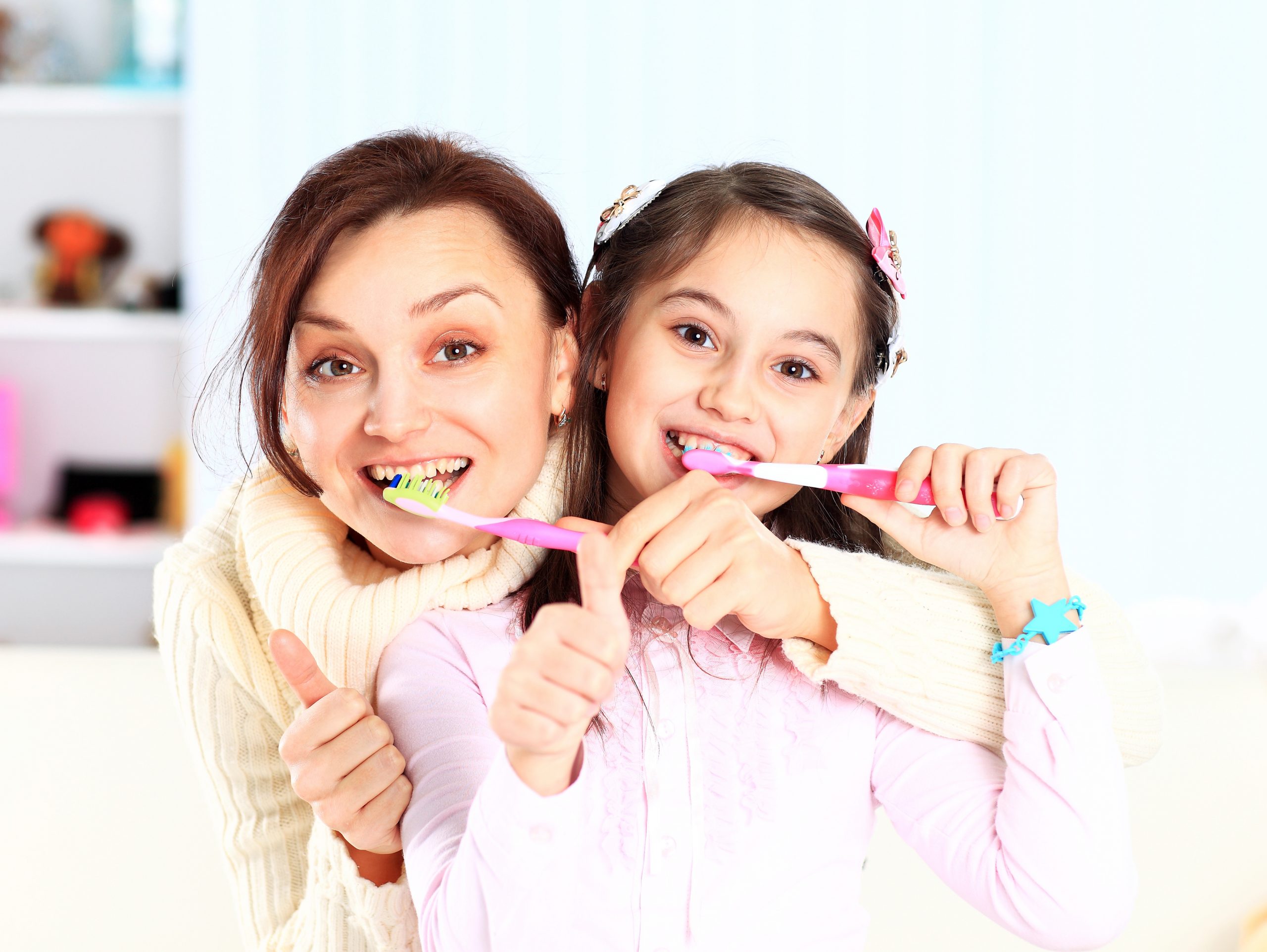 Mother and daughter brush their teeth.