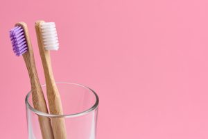 Two bamboo toothbrush close-up in glass on white background. Eco friendly and zero waste concept photo.