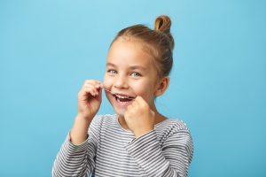 Isolated portrait - dental flush, caucasian child girl using flossing teeth and smiling