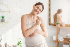 Young pregnant woman brushing teeth in bathroom