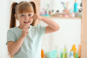 Cute little girl flossing her teeth in bathroom