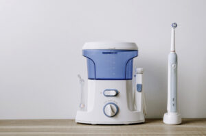 Irrigator and electric toothbrush on light background