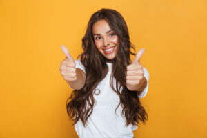 Image of happy young woman isolated over yellow background showing thumbs up gesture.