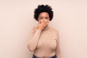 African american woman over isolated background covering mouth with hands