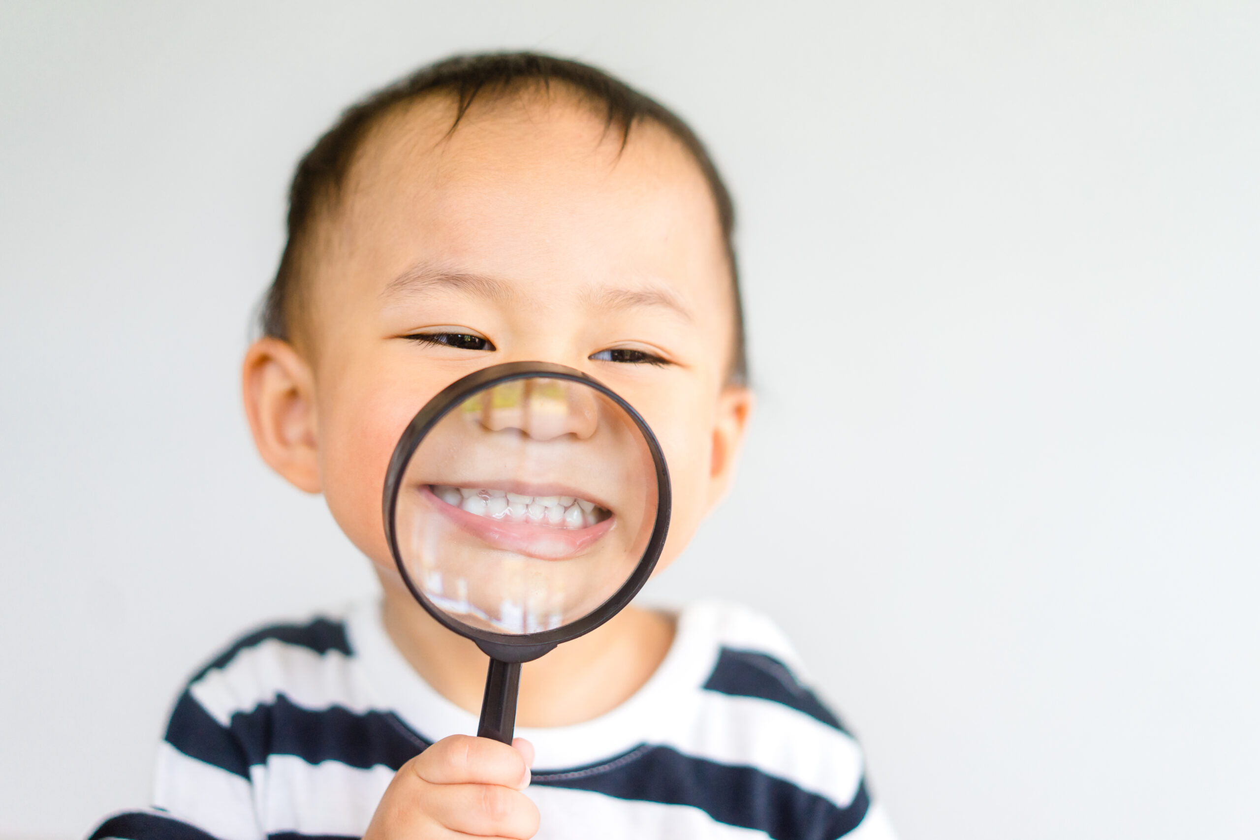 Little toddler boy child holding magnifying glass and showing fr