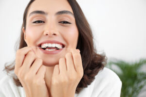 Beautiful young woman with dental floss in bathroom