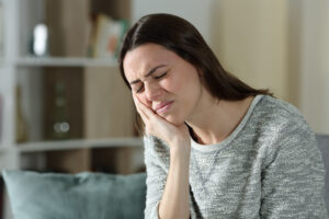 Stressed woman complaining suffering toothache sitting on a couch at home