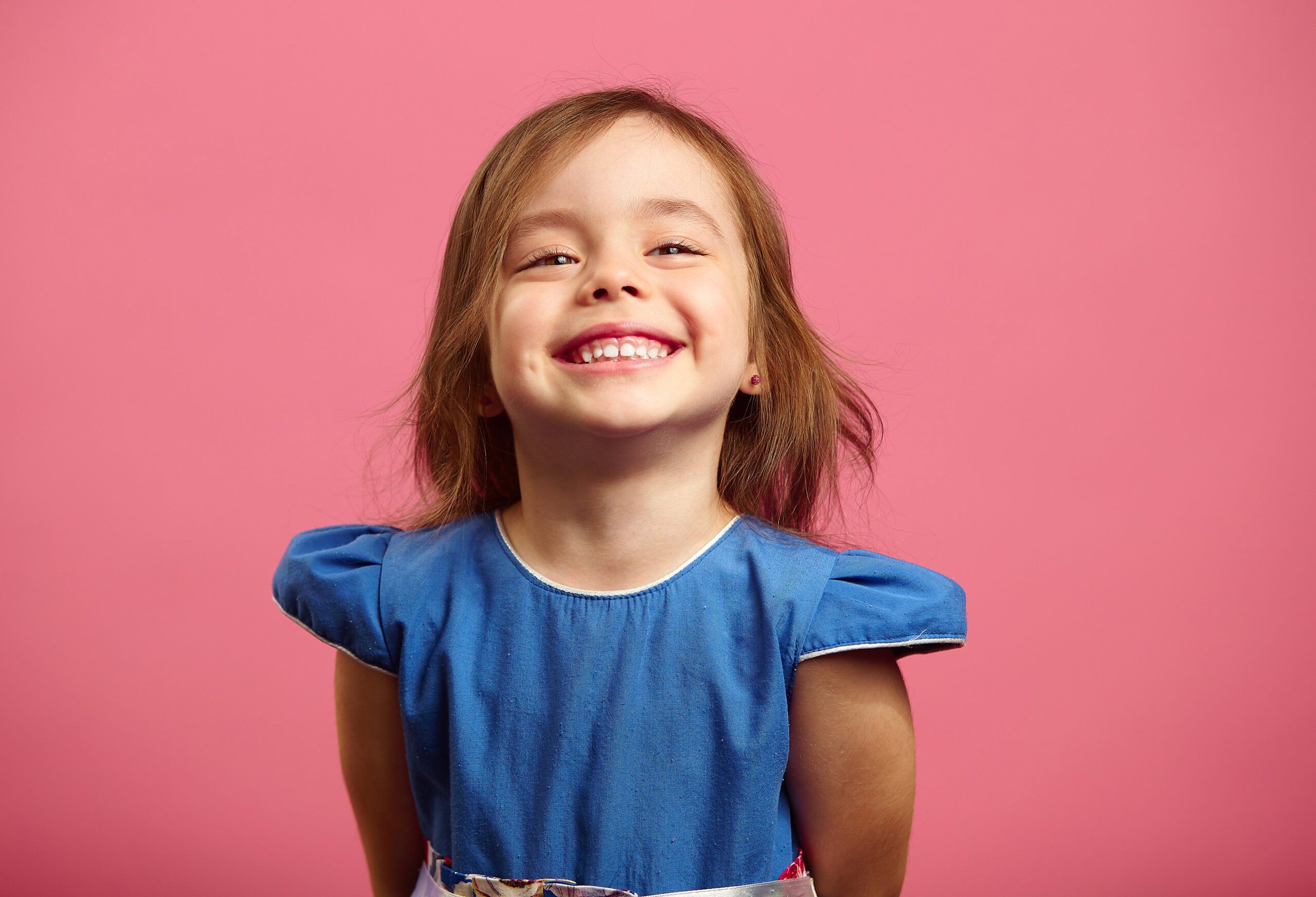 Female portrait of charming child of three years with a beautiful smile, cheerful shot on isolated pink.