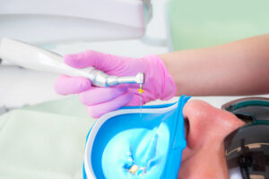 Macro photo of dental tools: drill and needle for treating root canals and pulpitis in a dentist's hand in a pink glove. Patient wearing sunglasses