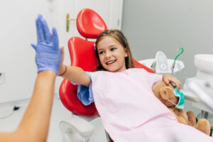 Cute little girl sitting on dental chair and having dental treatment.