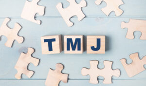Blank puzzles and wooden cubes with the text TMJ lie on a light blue background.