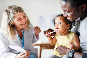 Dentist teaching a little girl how to brush her teeth