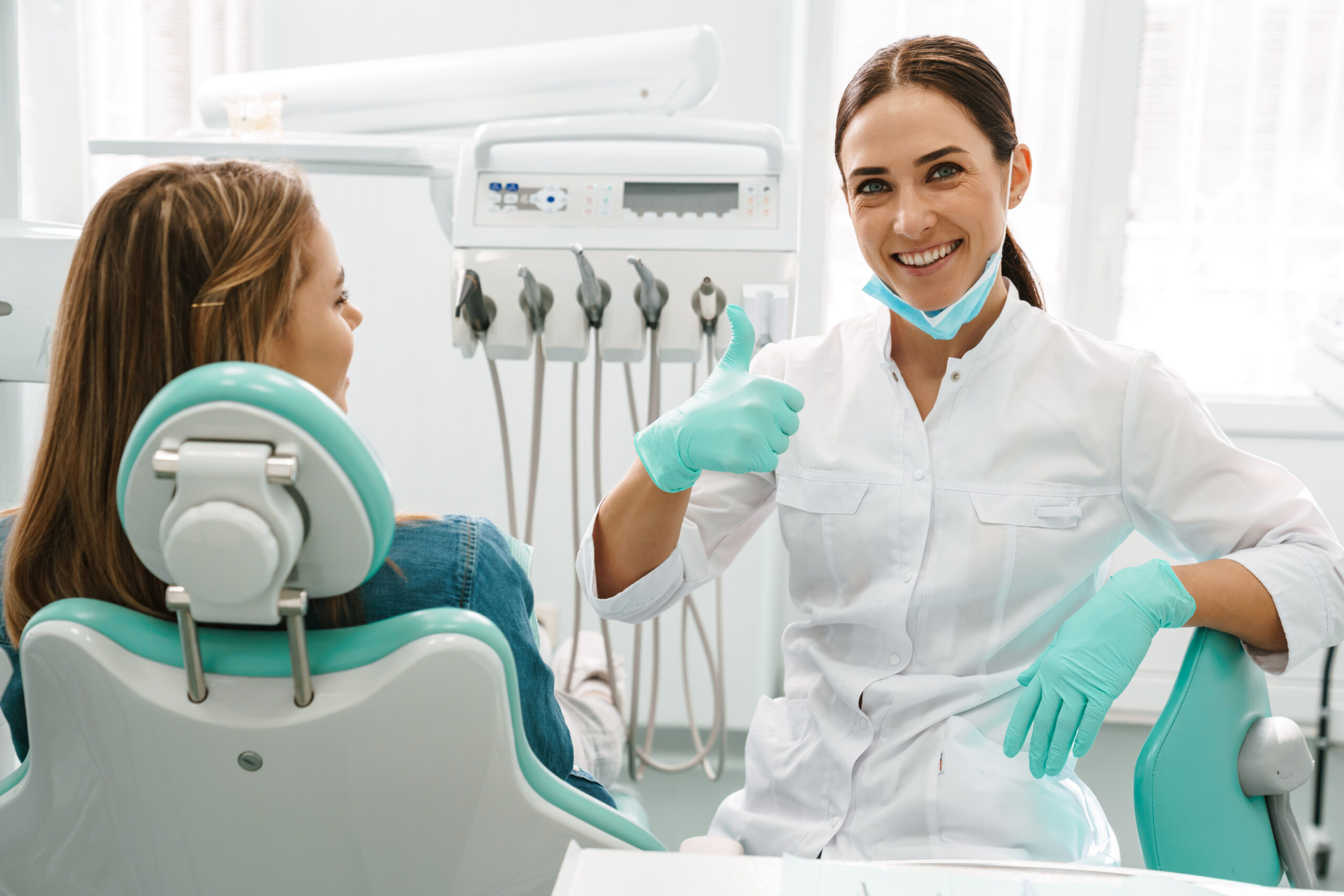 European mid dentist woman showing thumb up while working with patient in dental clinic