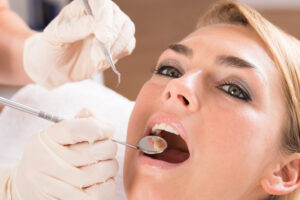 Closeup of dentist's hands examining female patient's teeth at clinic